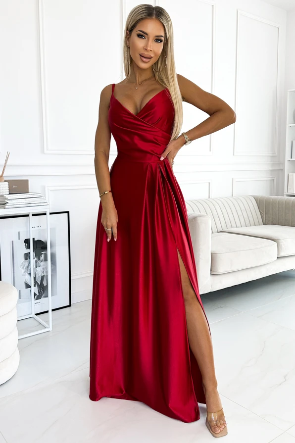 Na zdjęciu widoczna jest elegancka sukienka Chiara, wykonana z połyskującego materiału w intensywnym czerwonym kolorze. Sukienka Chiara ma długą, zwiewną spódnicę z efektownym rozcięciem oraz dopasowaną górę na cienkich ramiączkach.