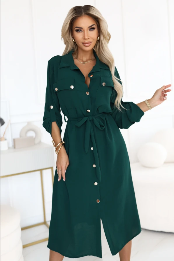 Modelka prezentuje elegancką zieloną sukienkę koszulową midi z możliwością podpięcia rękawów, idealną do pracy i na co dzień.